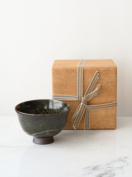 Ceramic bowl next to a wrapped gift box on a marble surface
